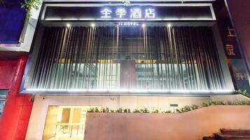 A hotel entrance with a modern facade, large glass windows, and a sign indicating it is a hotel.