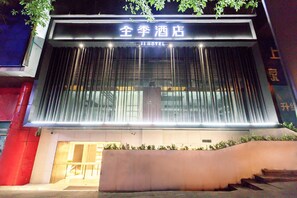 A hotel entrance with a modern facade, large glass windows, and a sign indicating it is a hotel. - Ji Hotel (Chongqing)