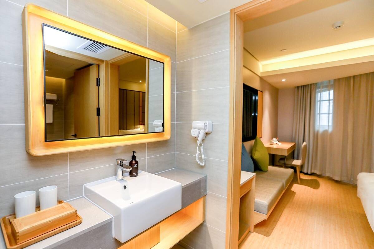 A modern bathroom with a large mirror, a sink, a hairdryer, and a telephone.