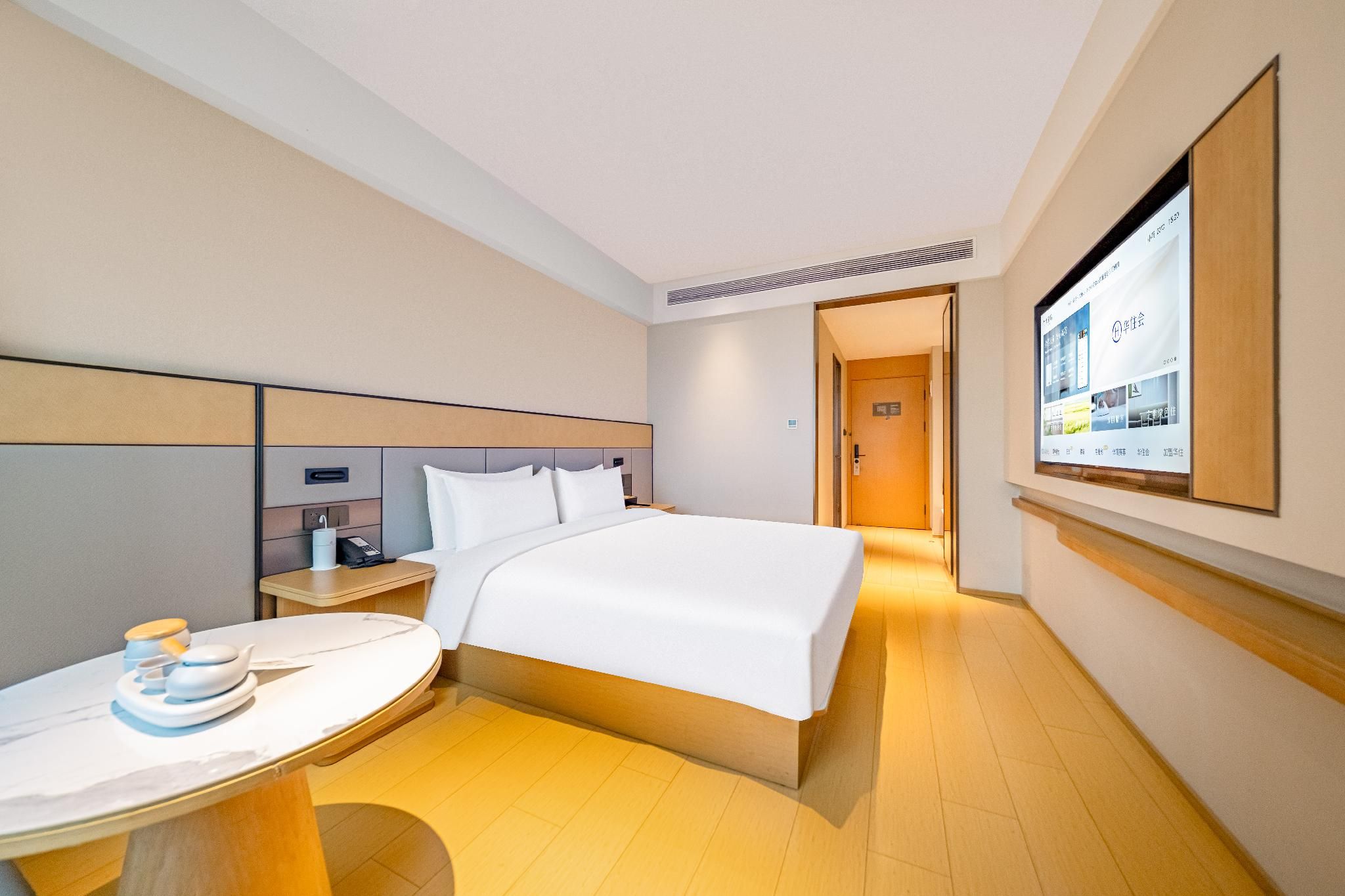 Una habitación de hotel con cama, mesita de noche y una televisión mostrando un menú.