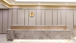 A reception desk with a marble top and a wooden counter, a wall-mounted sign with Chinese characters, and a modern ceiling with recessed lighting. - Ji Hotel (Chongqing)