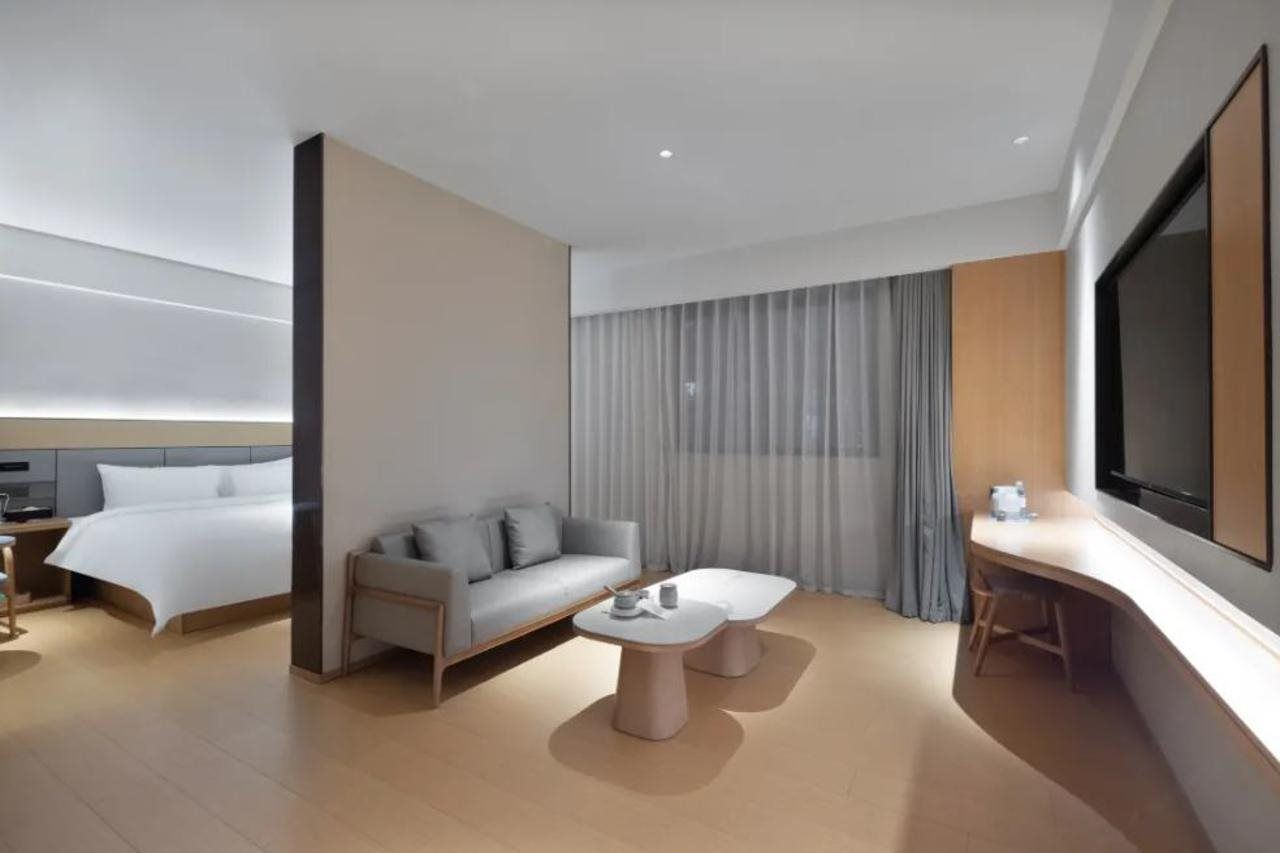 Una habitación de hotel moderna con cama, sofá, escritorio y televisor.
