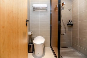 A modern bathroom with a toilet, a shower, and a hand dryer. - Ji Hotel (Chongqing)