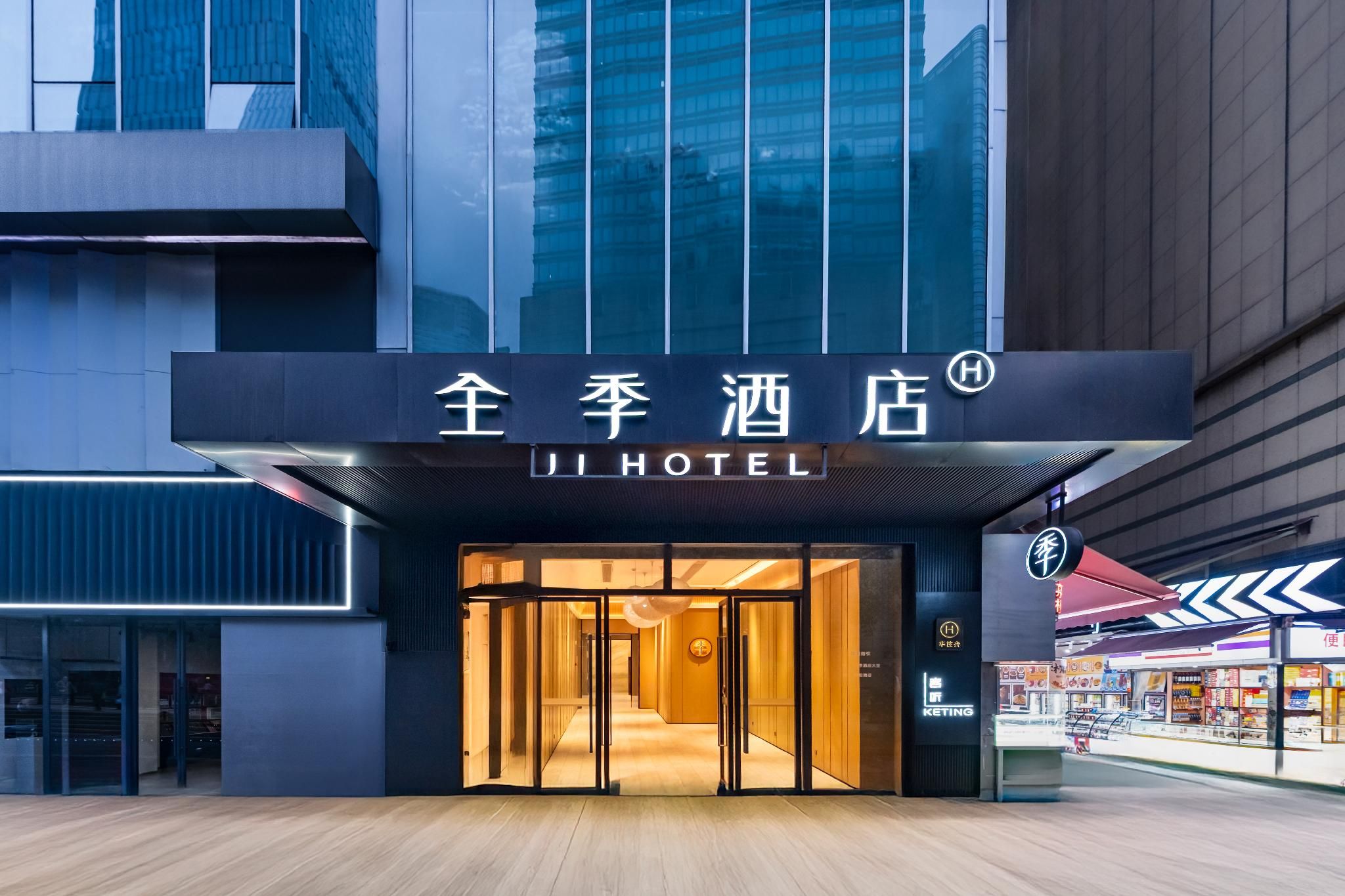 Entrada de hotel con diseño moderno, destacando un fachada de vidrio y un letrero con caracteres chinos.