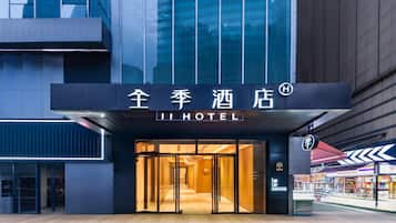A hotel entrance with a modern design, featuring a glass facade and a sign with Chinese characters.