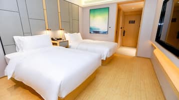 A hotel room with two beds, a nightstand, a painting, and a TV.