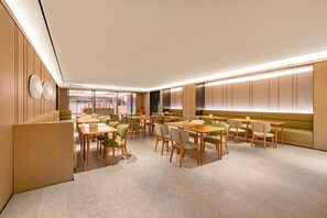 A modern dining area with tables and chairs, a reception desk, and a counter with a cash register. - Ji Hotel (Chongqing)