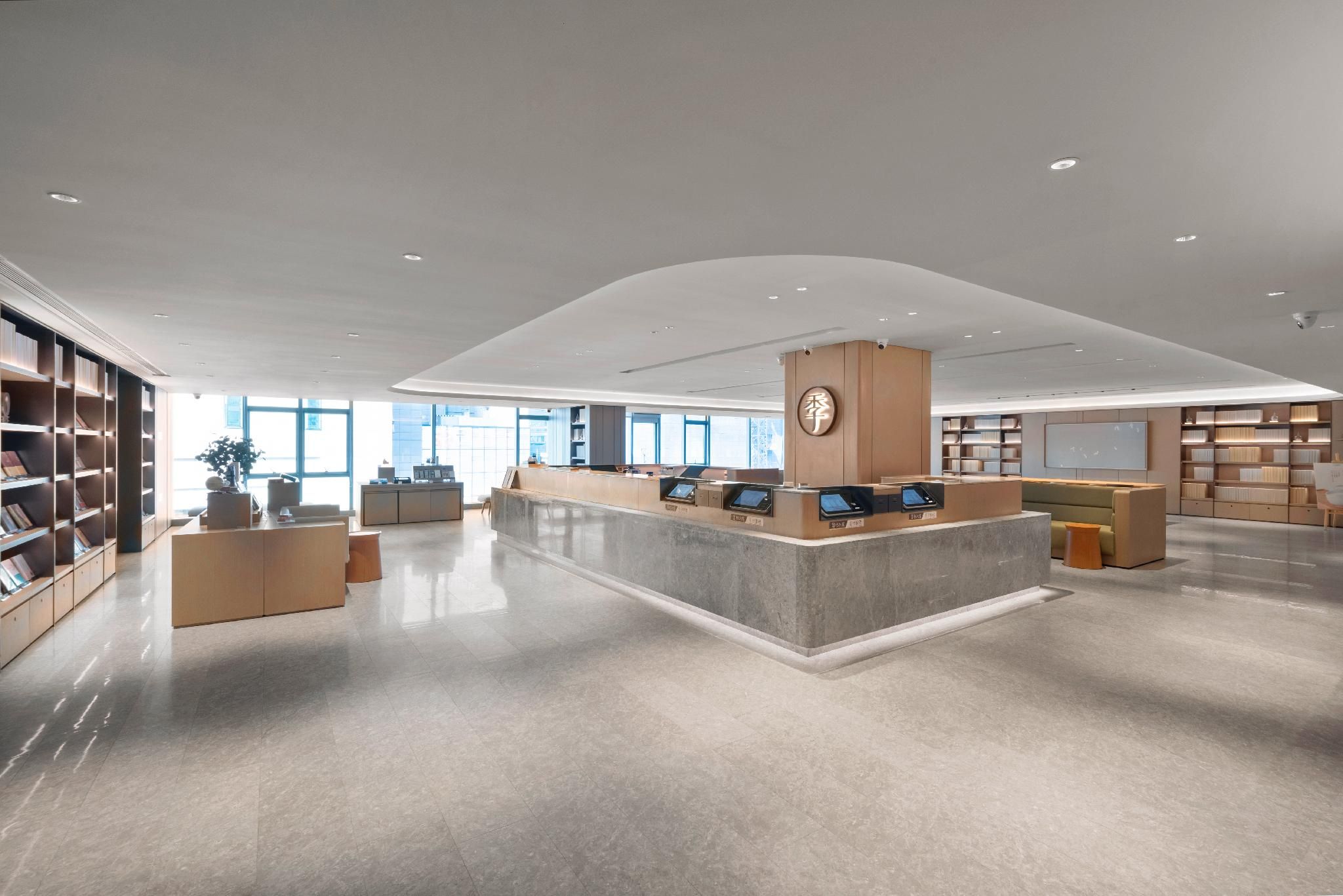 Una biblioteca amplia con un mostrador de recepción central, estanterías y un diseño moderno.