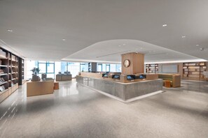A spacious library with a central reception desk, bookshelves, and a modern design. - Ji Hotel (Chongqing)