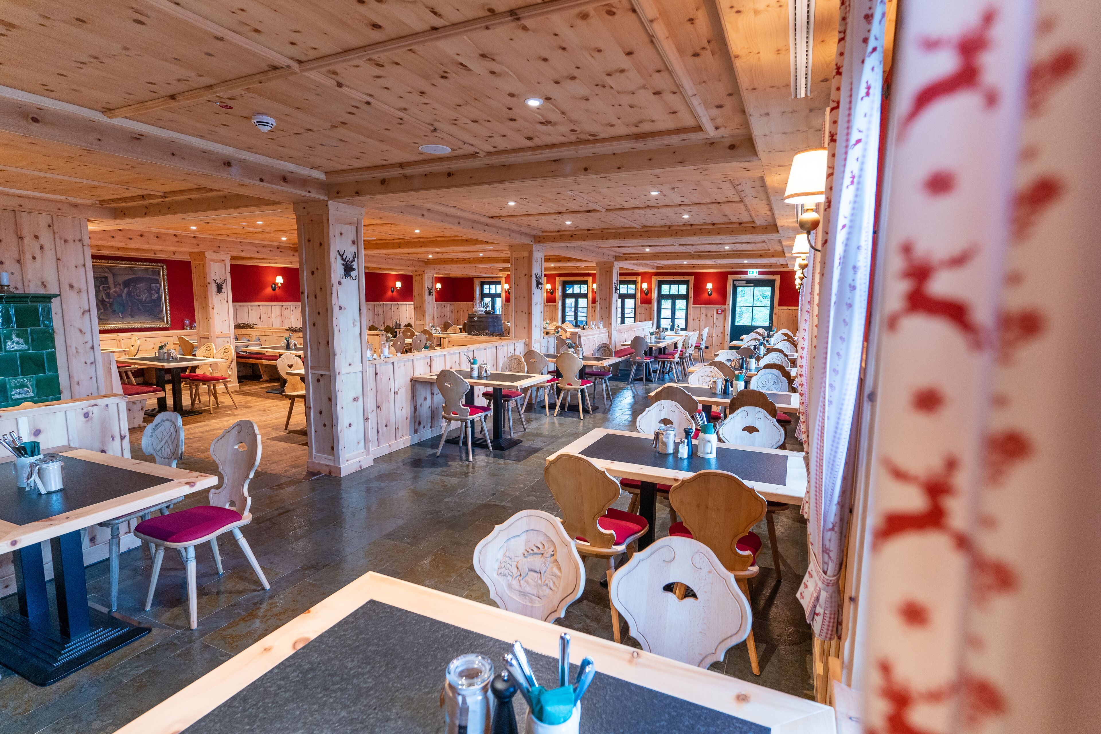 A spacious restaurant with wooden interiors, multiple dining tables, and chairs.