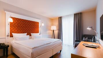 Une chambre d’hôtel avec un grand lit, deux lampes de chevet, un bureau avec une lampe, une chaise et une vue sur l’extérieur par une fenêtre.