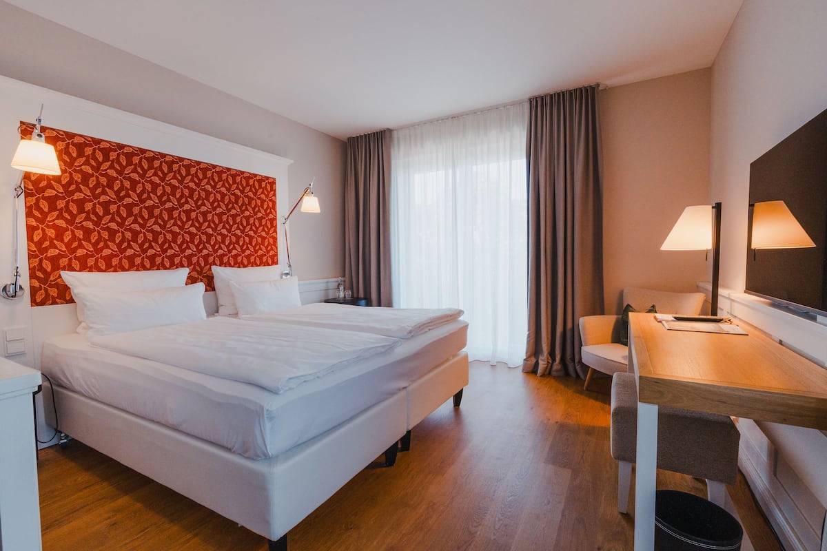 A hotel room with a large bed, a desk, and a television.