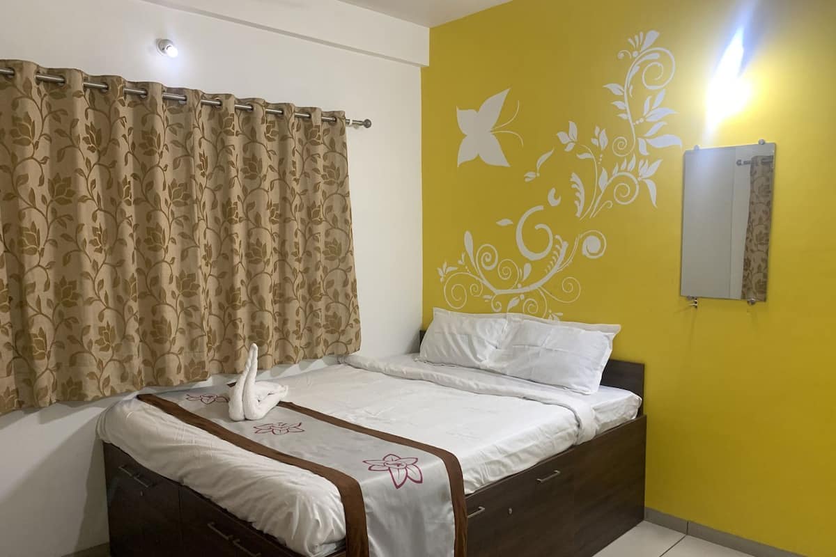 Un dormitorio con una cama, cortinas, una pared con diseño decorativo y un espejo.