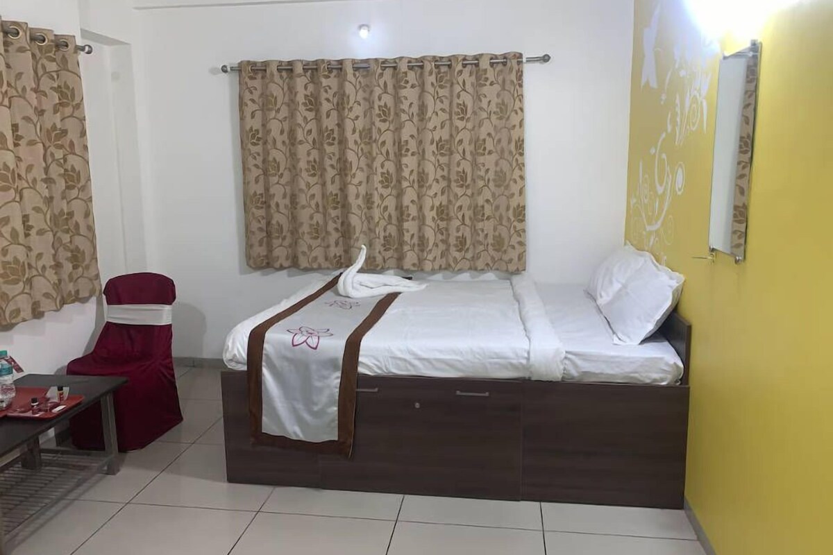 A hotel room with a bed, a chair, and a small table.