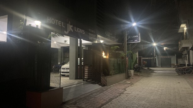 En hotellentrédörr med en skylt som visar texten ”Hotel Lions”, och en synlig bil parkerad utanför.
