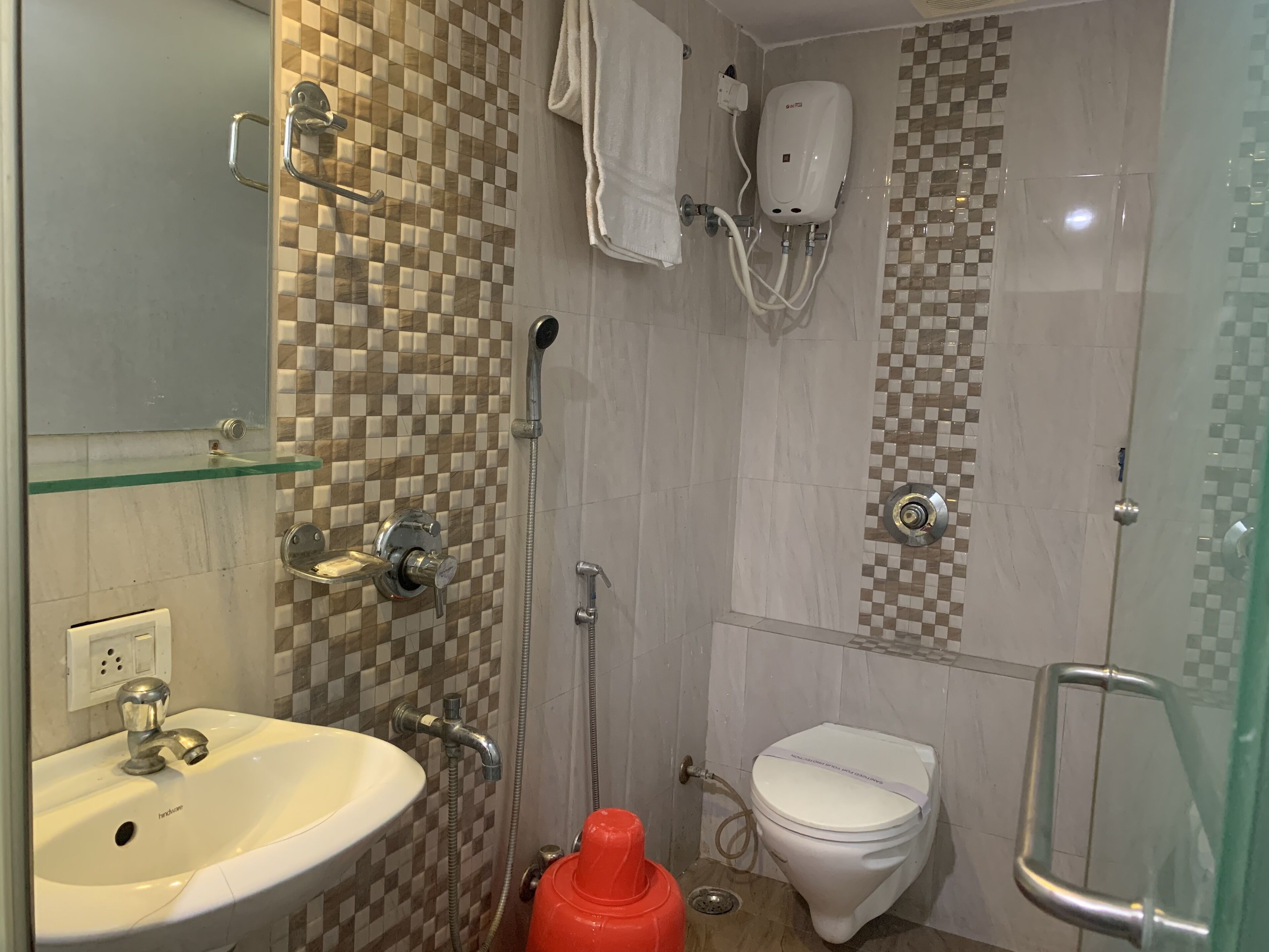 A bathroom with a glass shelf, a sink, a toilet, and a shower.