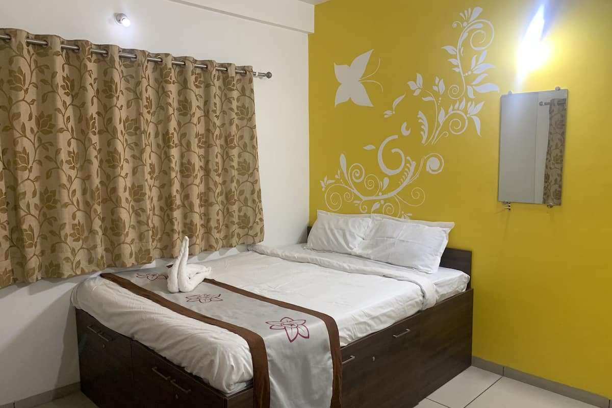 Un dormitorio con cama, cortinas, una pared con diseño decorativo y un espejo.