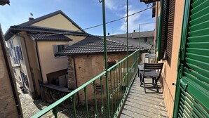 Un estrecho callejón con un muro de piedra, un banco pequeño y una verja verde.