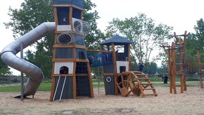 A playground with a slide, climbing structures, and a netted play area.