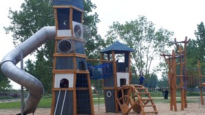 A playground with a slide, climbing structures, and a wooden playhouse. - "La Fautaise" house in residence with swimming pool, near beach. (La Faute-sur-Mer)
