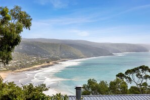 A coastal landscape with a beach, ocean, and hills in the background.