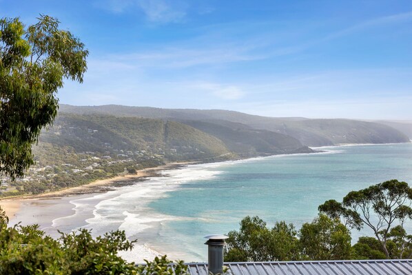 Eine Küstenlandschaft mit Strand, Meer und Hügeln im Hintergrund.
