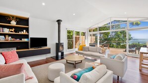 Un salon moderne doté d’une cheminée, de grandes fenêtres et offrant une vue sur l’extérieur.