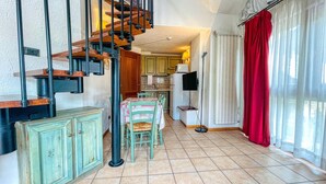 A kitchen with a dining area, a staircase, and a red curtain.