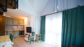 A compact kitchen with a dining area, a small table, and a red chair.