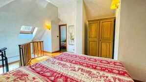A bedroom with a large bed, a wooden door, and a skylight.