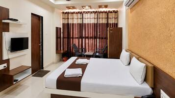 Een hotelkamer met een bed, televisie, bureau, stoelen en een airconditioner.