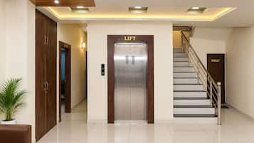 Een hotel lobby met een lift, een trap en een toilet.