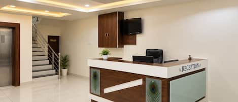 Un mostrador de recepción con diseño de pavo real, una escalera y un televisor montado en la pared.