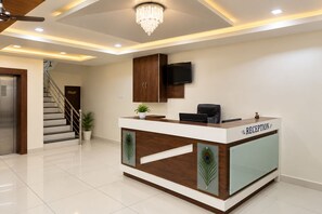 Un mostrador de recepción con diseño de pavo real, una escalera y un televisor montado en la pared.