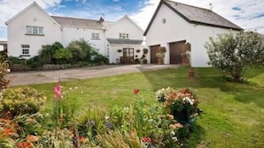 A white two-story house with a front garden and a driveway.
