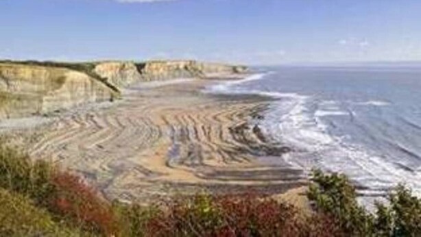 A coastal landscape with cliffs and a beach.
