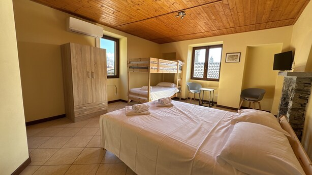 A room with bunk beds, a desk, a chair, a wardrobe, and a television.