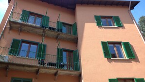 A multi-story building with balconies, green shutters, and a pink facade.