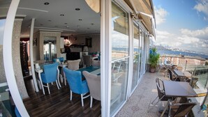 A balcony with a dining area, a kitchen, and a view of the city. - Crowned Hotel (Istanbul)