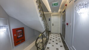 A hallway with a staircase, a fire hose cabinet, and a door marked with the number 502. - Crowned Hotel (Istanbul)