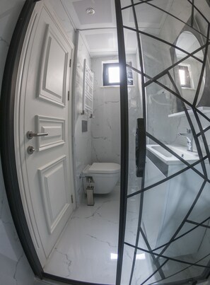 A bathroom with a toilet, sink, and shower.