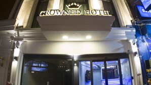 The exterior of the Crowne Plaza Hotel with its illuminated signage and entrance doors. - Crowned Hotel (Istanbul)