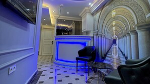 A hotel lobby with a reception desk, seating area, and a staircase leading to upper floors. - Crowned Hotel (Istanbul)