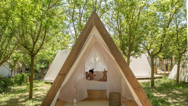 A triangular wooden tent with a canopy, a mattress, and a small table. - wecamp Santa Cristina (Santa Cristina de Aro)