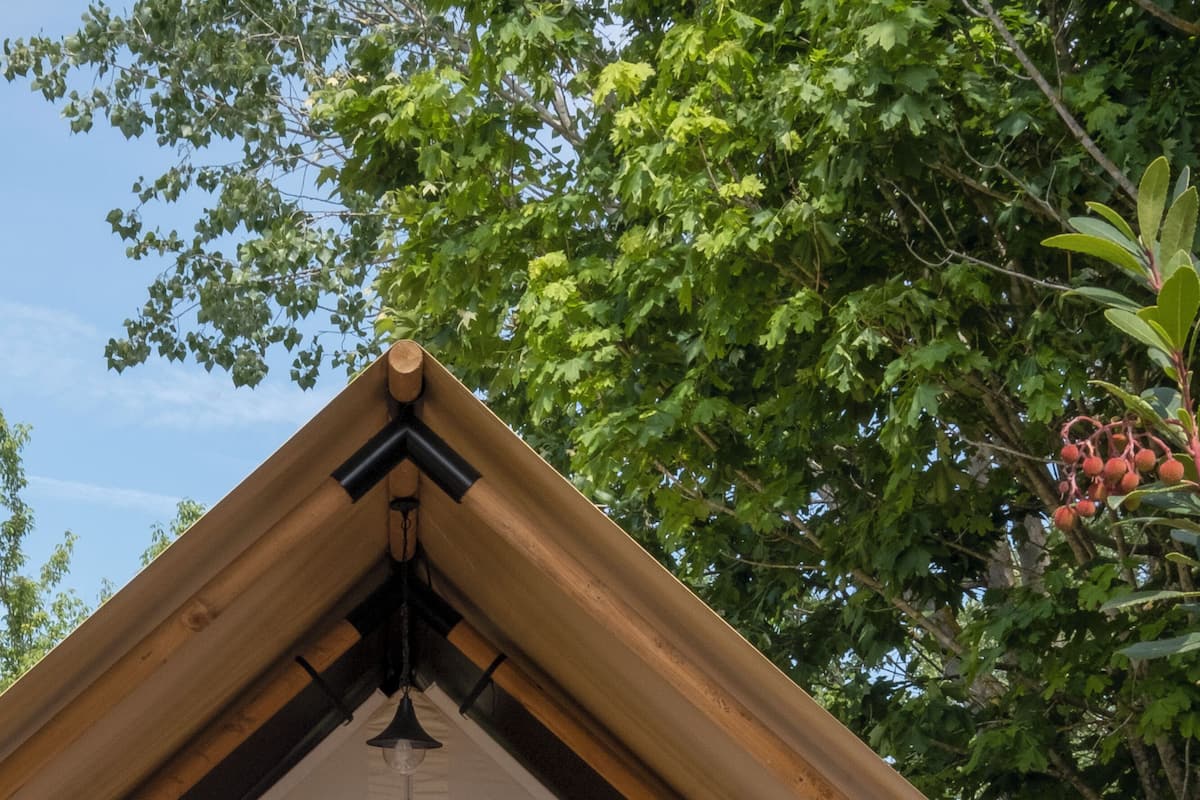 Un espacio al aire libre acogedor con un pérgola de madera, un banco acolchado y una pequeña mesa.
