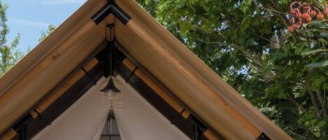 Un espacio al aire libre acogedor con un pérgola de madera, un banco acolchado y una pequeña mesa.