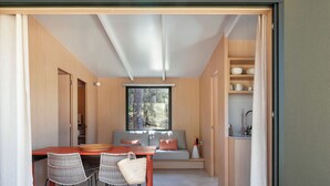 A modern interior with a dining area, kitchen, and seating space. - wecamp Santa Cristina (Santa Cristina de Aro)