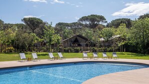 A swimming pool with lounge chairs and a wooden deck. - wecamp Santa Cristina (Santa Cristina de Aro)