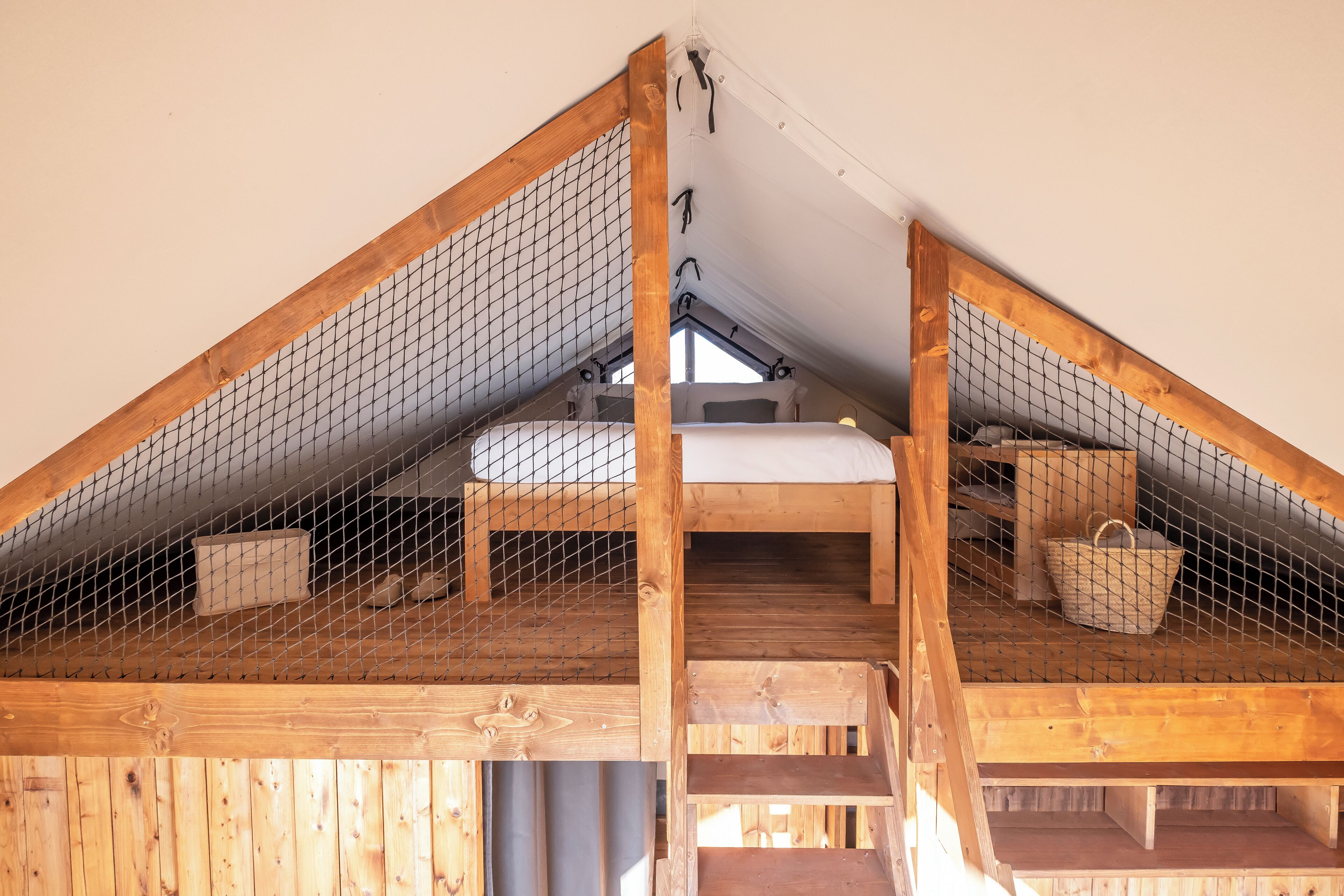 Dormitorio tipo loft con escalera de madera, literas y una ventana.