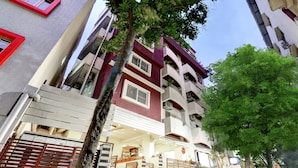 A multi-story building with balconies, a gated entrance, and a tree in the foreground. - Treebo Saga Apartment (Bengaluru)